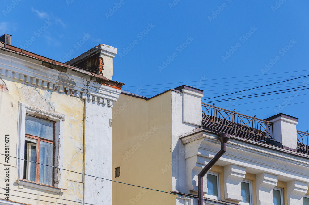 part of an old building with crumbling plaster, broken wooden window, blue sky