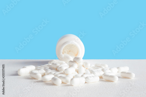 Pills spilled out of white bottle. Mock up for special offers as advertising or other ideas. Medical, pharmacy and healthcare concept. Copy space. Empty place for text or logo on blue background.