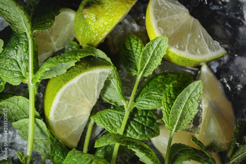 Lime slices with ice and mint on dark background.