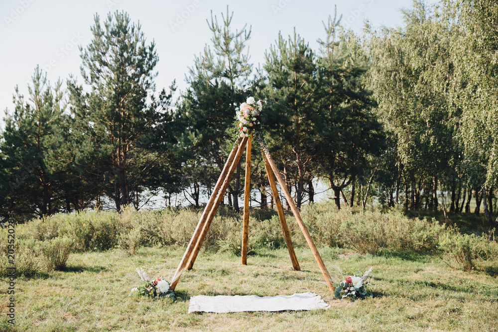 arch for the wedding ceremony of wooden logs stands in forest glade among the trees arch for the wedding ceremony of wooden logs stands in forest glade among the trees