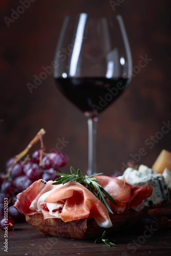 Prosciutto with rosemary and glass of red wine .