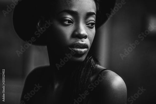 Portraite photo of adorable african woman. Pretty girl smiling and take her hand to hat on the head.