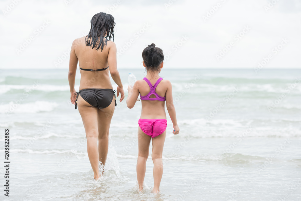 Mother and daughter walking on the beach.