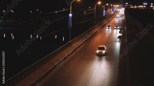 Traffic in night city, cars drivie over bridge, urban lights scene photo