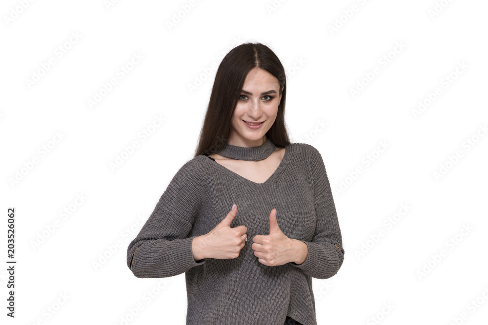 Beautiful brunette girl stands on white background and shows ok and smiles Beautiful brunette girl stands on white background and shows ok and smiles