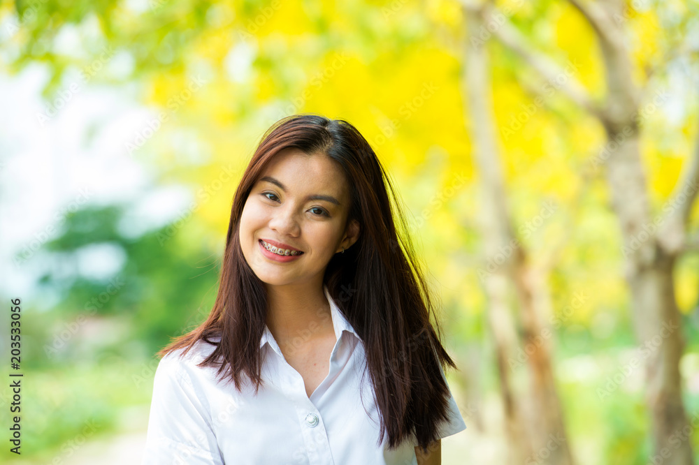 portrait of the happy beautiful Thai student with university uniform standing and smiling on the yellow tree background portrait of the happy beautiful Thai student with university uniform standing and smiling on the yellow tree background