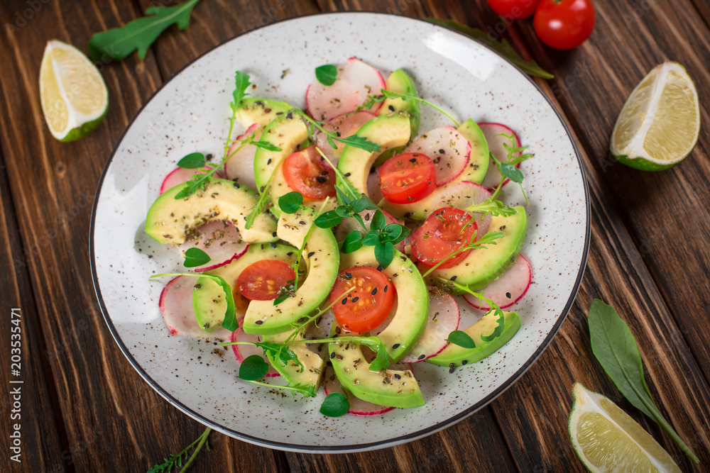 Vegetable salad with avocado, arugula, radish, lime and olive oil. Dietary healthy food. Wooden rustic background. Top view Vegetable salad with avocado, arugula, radish, lime and olive oil. Dietary healthy food. Wooden rustic background. Top view