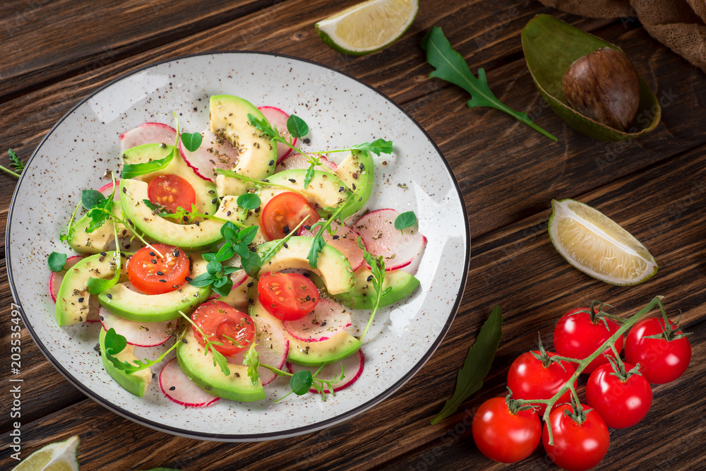 Vegetable salad with avocado, arugula, radish, lime and olive oil. Dietary healthy food. Wooden rustic background. Top view Vegetable salad with avocado, arugula, radish, lime and olive oil. Dietary healthy food. Wooden rustic background. Top view