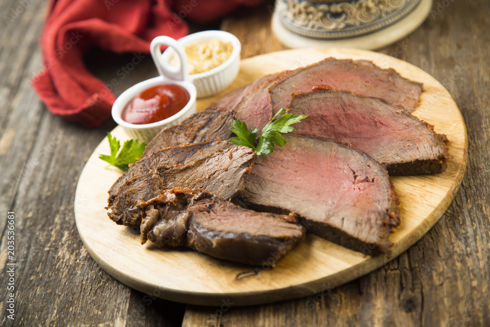 Sliced roast beef on the wooden cutting board with sauces Sliced roast beef on the wooden cutting board with sauces