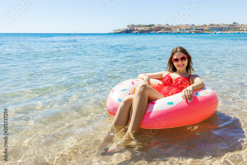 Beautiful young woman relaxing on inflatable donut in sea