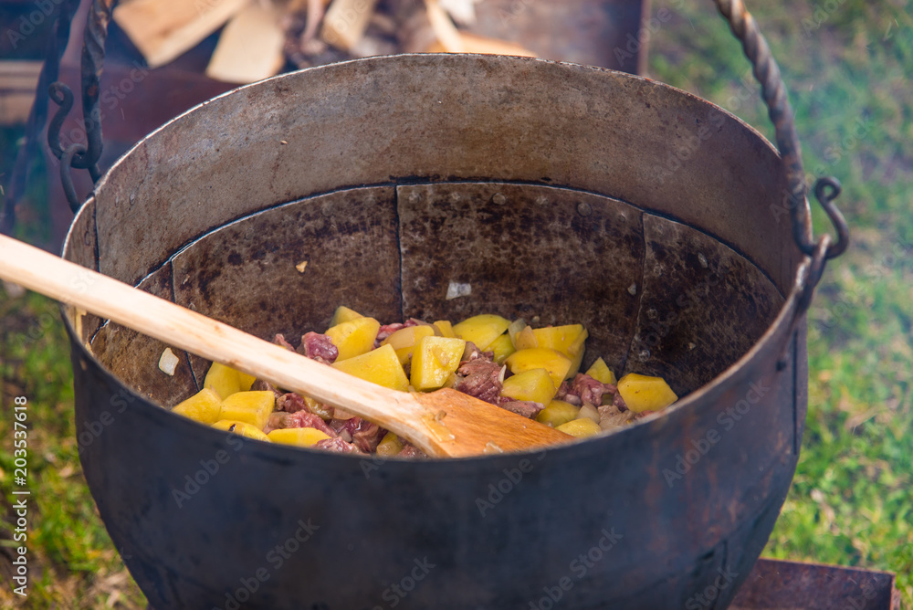 Stewed potatoes with meat in an old iron pot outdoors Stewed potatoes with meat in an old iron pot outdoors