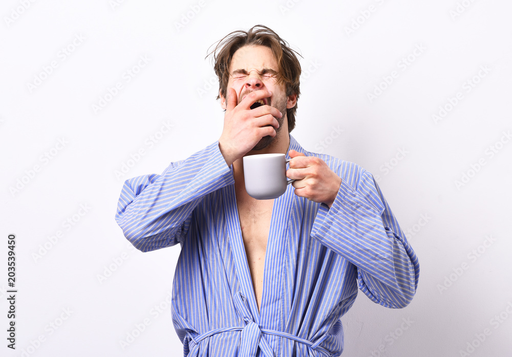 Sportsman with sleepy face stands in bathrobe with mug. Sportsman with sleepy face stands in bathrobe with mug.
