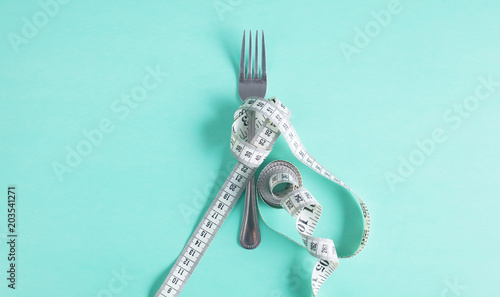 The fork is wrapped with a measuring tape on the table. Diet photo