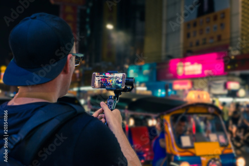 Man with backpack holding a steadycam gimbal with smart phone in bangkok