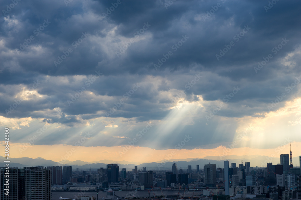 Top view of modern city with lights of sunset through clouds