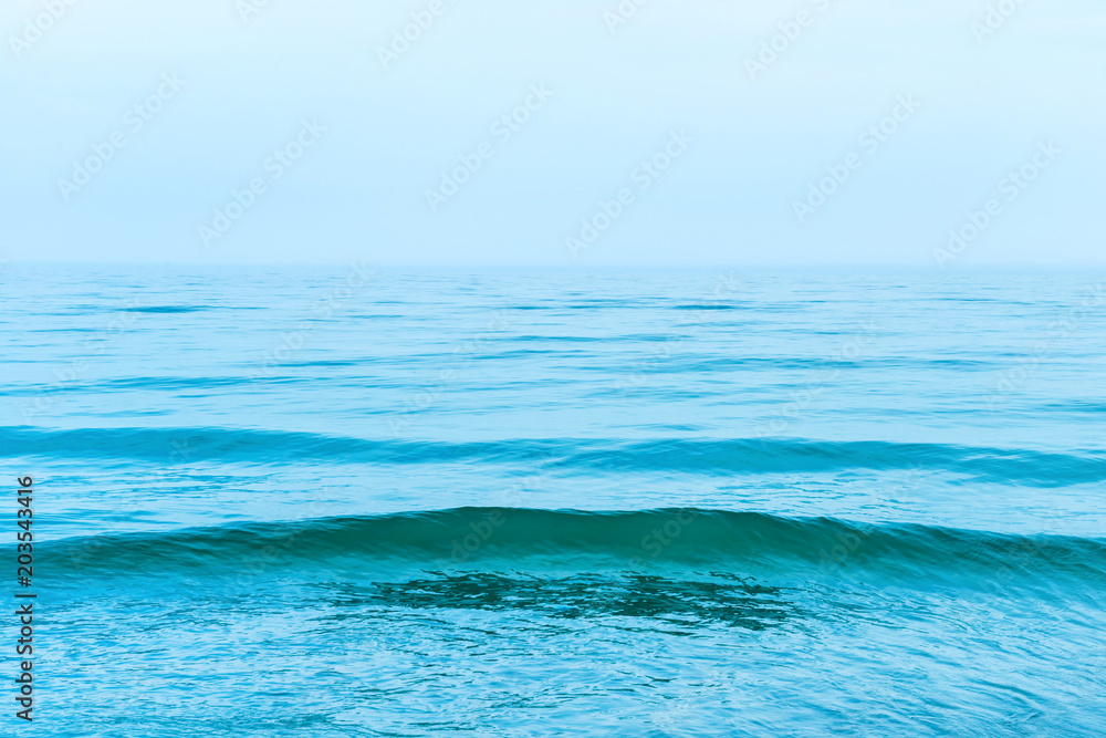 Obraz premium Blue sea water with waves and white clouds on the sky. Calm tropical landscape