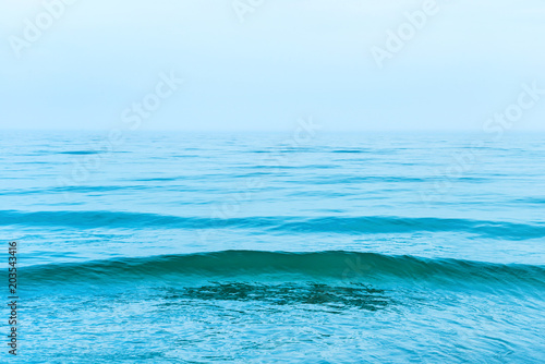 Blue sea water with waves and white clouds on the sky. Calm tropical landscape