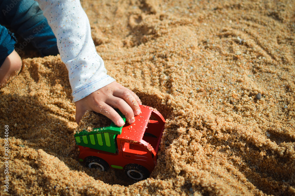 Child playing with his truck toy on a sunny day background Child playing with his truck toy on a sunny day background