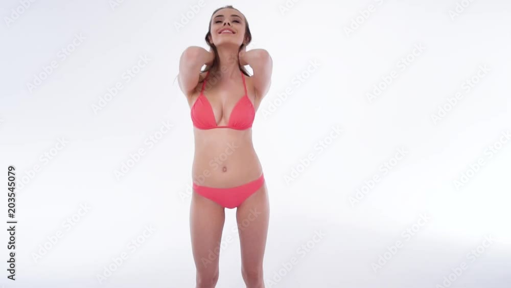 Pretty young brunette girl in red bikini posing over white studio wall background Pretty young brunette girl in red bikini posing over white studio wall background