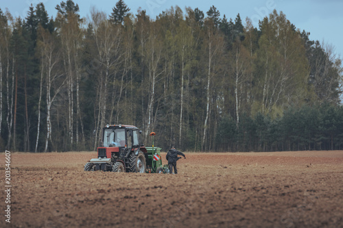 Land being cultivated and prepared for sowing with a tractor. Crispy texture in the soil. Old russian tractor with modern sow machine attached. Wheel, gauges and cabin.