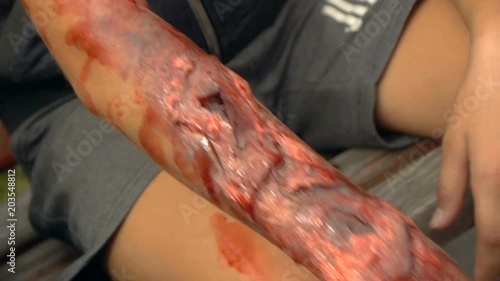 Fake wound on the guy's hand, bleeding wound on the arm of the zombie, halloween make-up photo