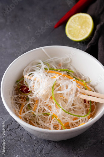 Bean thread noodles salad with cucumber and carrot on a plate close-up.