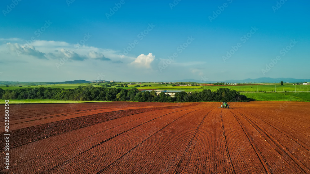 Aerial shot of  Farmer with a tractor on the agricultural field sowing.