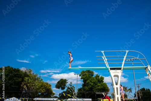 A girl jumping off of a diving board up high blue sky photo