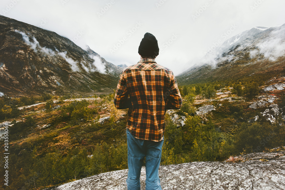 Man standing alone in foggy forest mountains enjoying view Travel adventure lifestyle concept active vacations in Norway