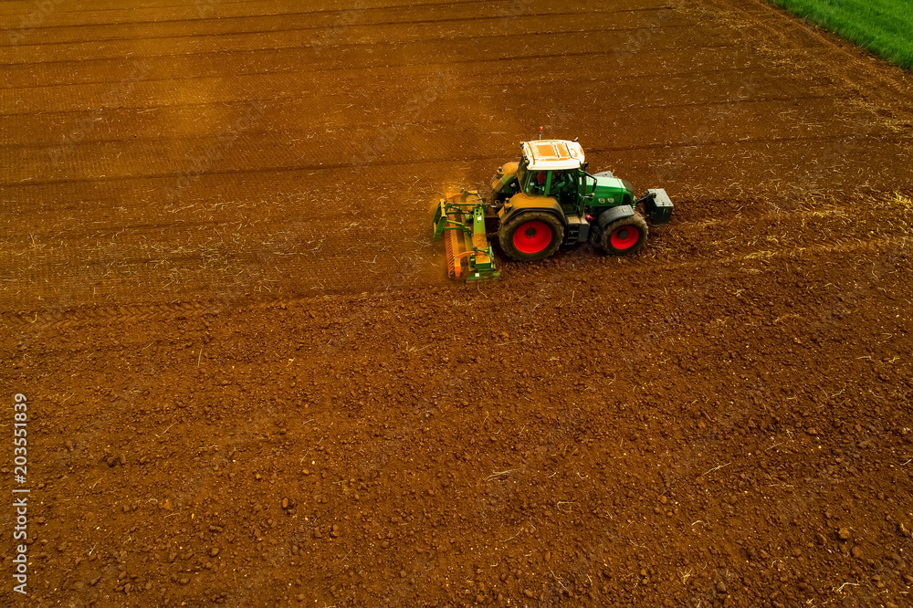 Obraz premium Aerial shot of Farmer with a tractor on the agricultural field sowing.