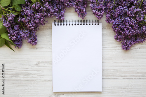 A bouquet of lilac flowers with notebook on a white wooden background. Copy space. Mothers Day. Top view.