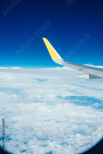 "Adventure, travel, transport concept. View from plane window at sky with  clouds and wing"