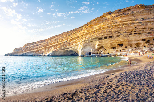 Fotografie Matala beach with caves on the rocks that were used as a roman cemetery and at t