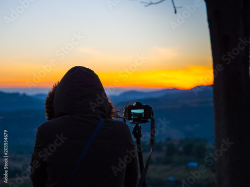 travel and photographer concept from backside of woman with hoodie cloth stand and see mountain view with take picture by her camera