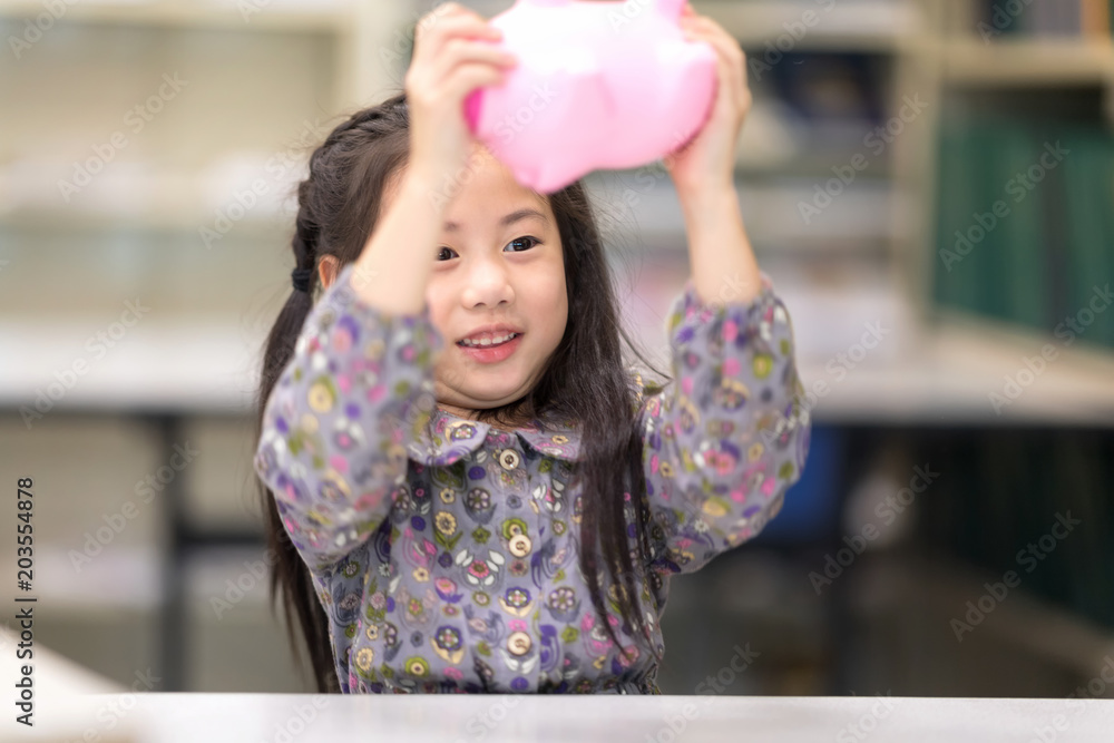 Happy kids Playing and raised a Pink Saving Pig Jar in the Library. Setup studio shooting. Happy kids Playing and raised a Pink Saving Pig Jar in the Library. Setup studio shooting.