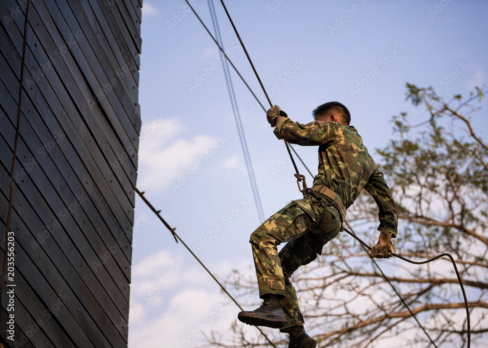 Soldier training rappel with rope. Military man does hanging on climbing  equipment. Stock Photo