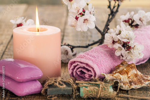 Soap with rolled towel  sea shell and  burning candle with flowering branch of apricot tree