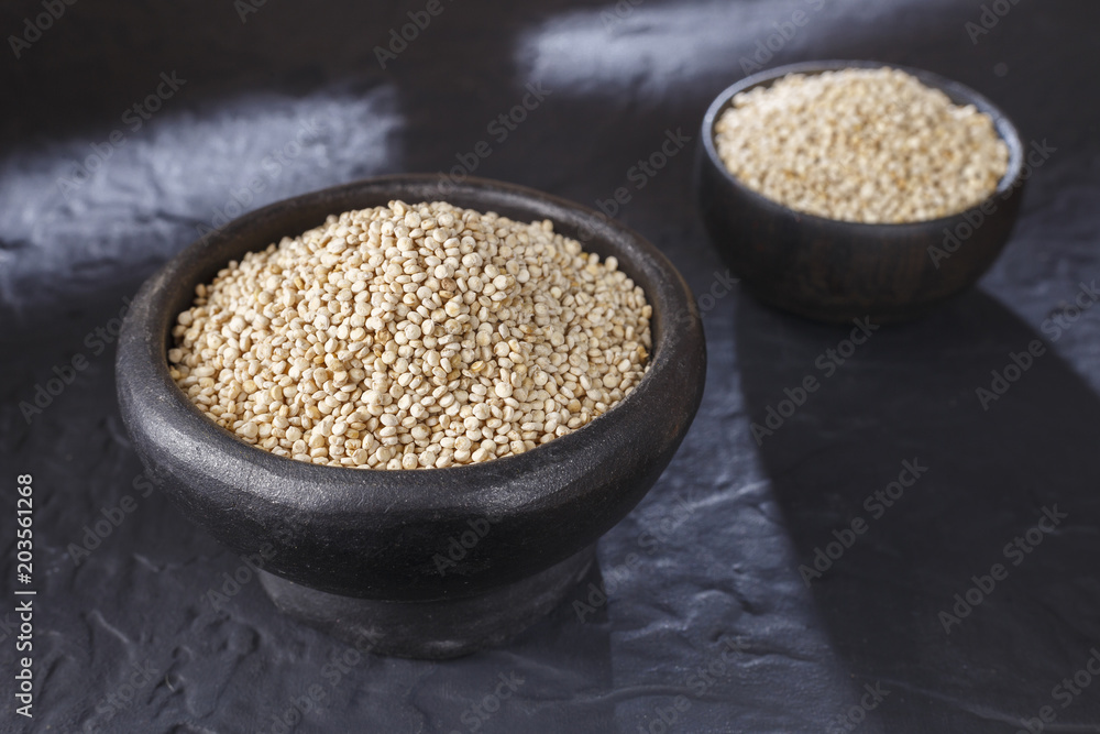 Quinoa grains with spoon and bowl on black background Quinoa grains with spoon and bowl on black background