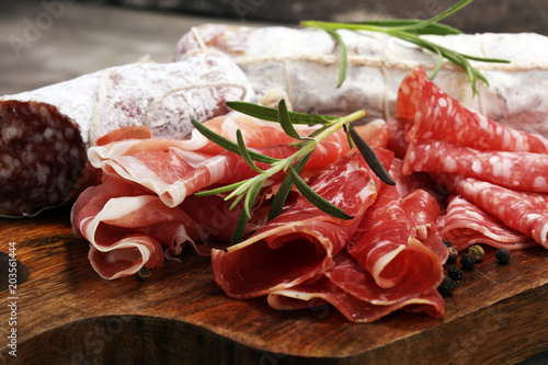 Food tray with delicious salami, prosciutto crudo,  fresh sausages and herbs. Meat platter with selection