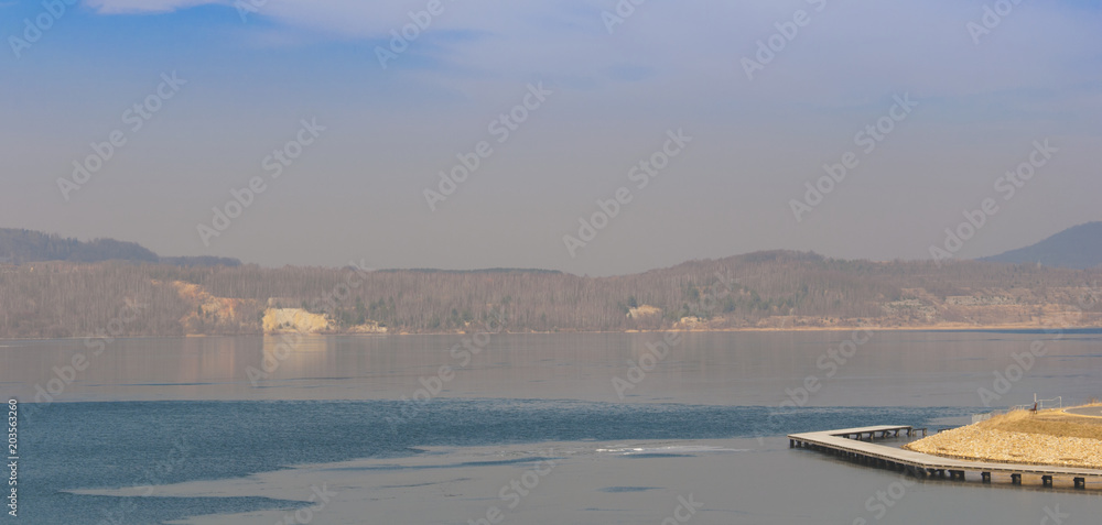 The Berzdorfer See (Berzdorfer lake) in east Germany in foggy weather with thin layer of ice on the surface of water. The Berzdorfer See (Berzdorfer lake) in east Germany in foggy weather with thin layer of ice on the surface of water.