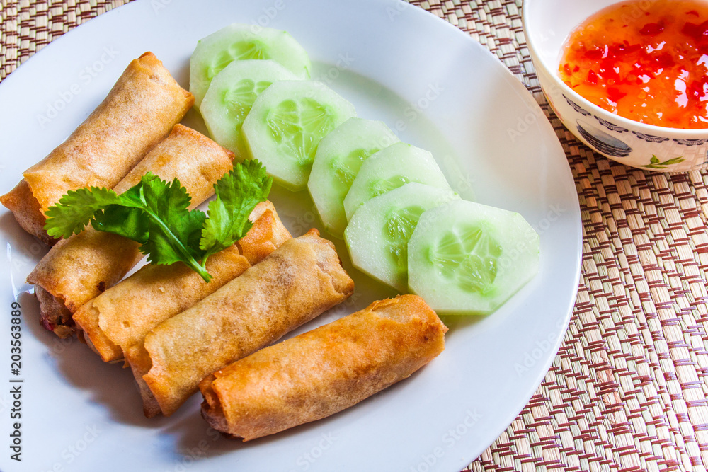 Spring rolls with Thai sweet chili sauce with cucumber slices and coriander