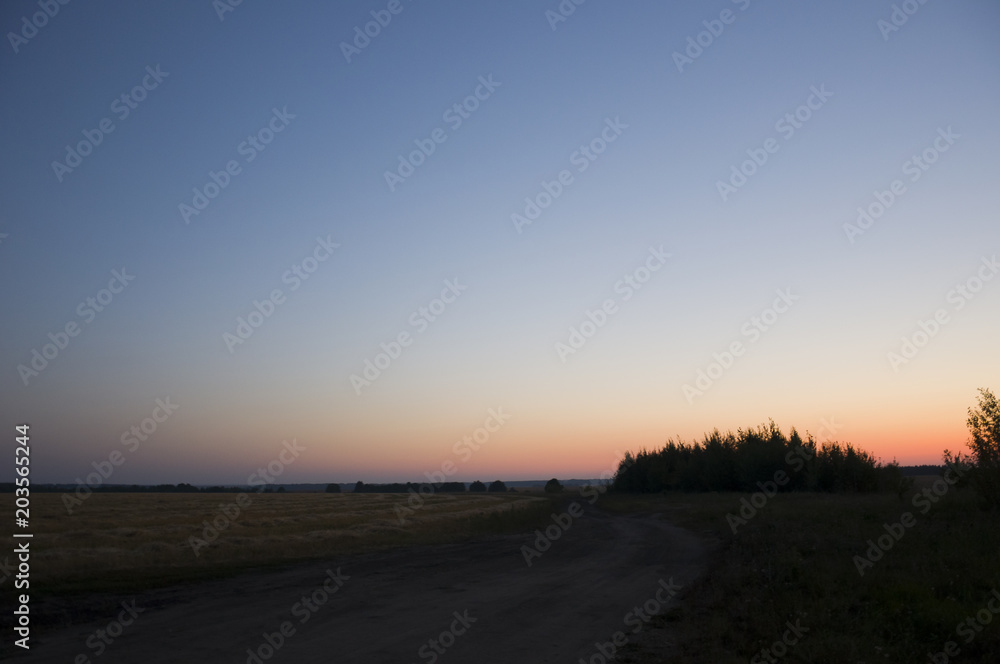Sundown and sunrises. bright night. dark blue sky with tints of orange, red, yellow and much clouds. Silhouettes of forests far away on the background of heaven Sundown and sunrises. bright night. dark blue sky with tints of orange, red, yellow and much clouds. Silhouettes of forests far away on the background of heaven