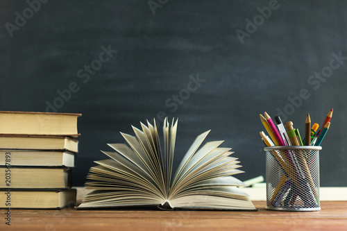 Foto Textbooks and school supplies on a table, against a chalkboard background with chalk