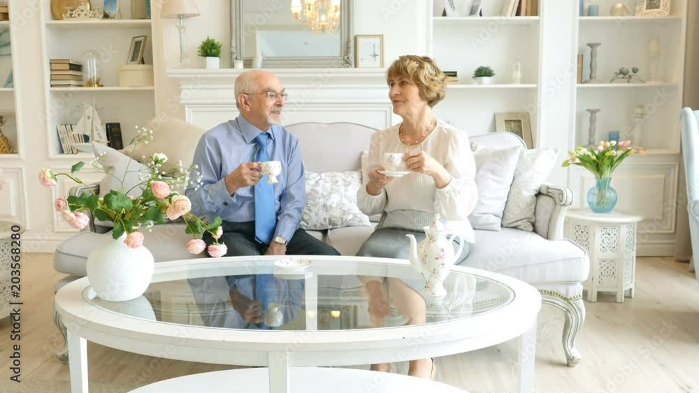 Happy caucasian couple of retirement age are spending time together sitting at a table and drinking coffee or tea Happy caucasian couple of retirement age are spending time together sitting at a table and drinking coffee or tea