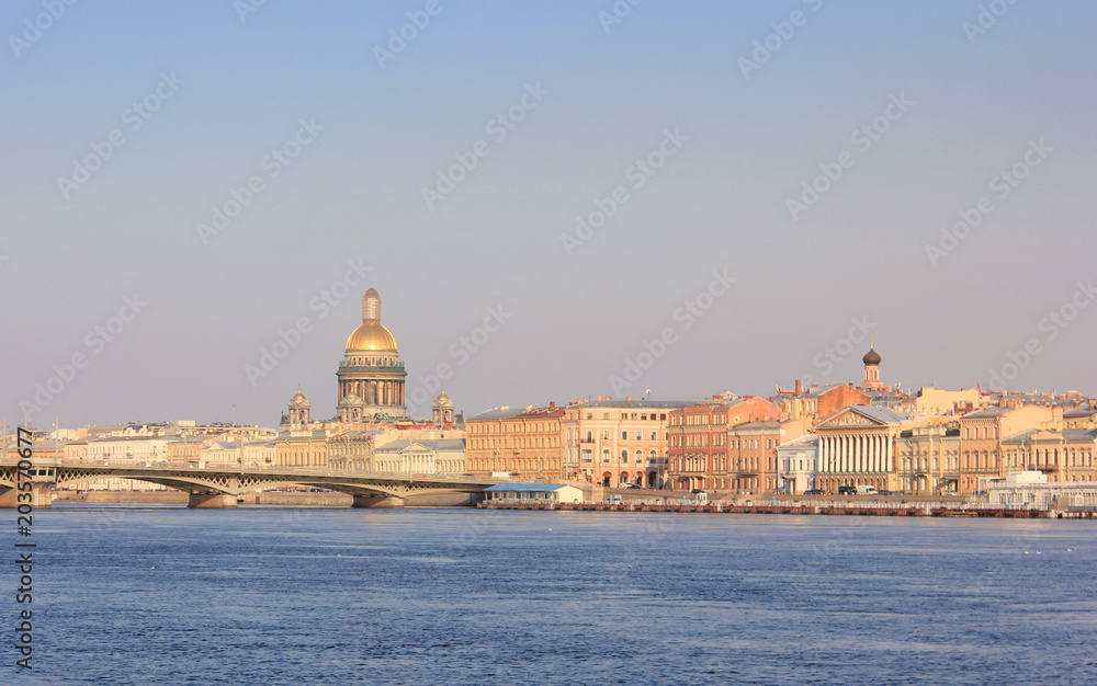 Sunset Skyline of St. Petersburg City with Saint Isaac's Cathedral, Historic Bridge and Old Buildings Architecture in Russia. Cityscape View with Classic Houses on River Embankment at Dusk Background.
