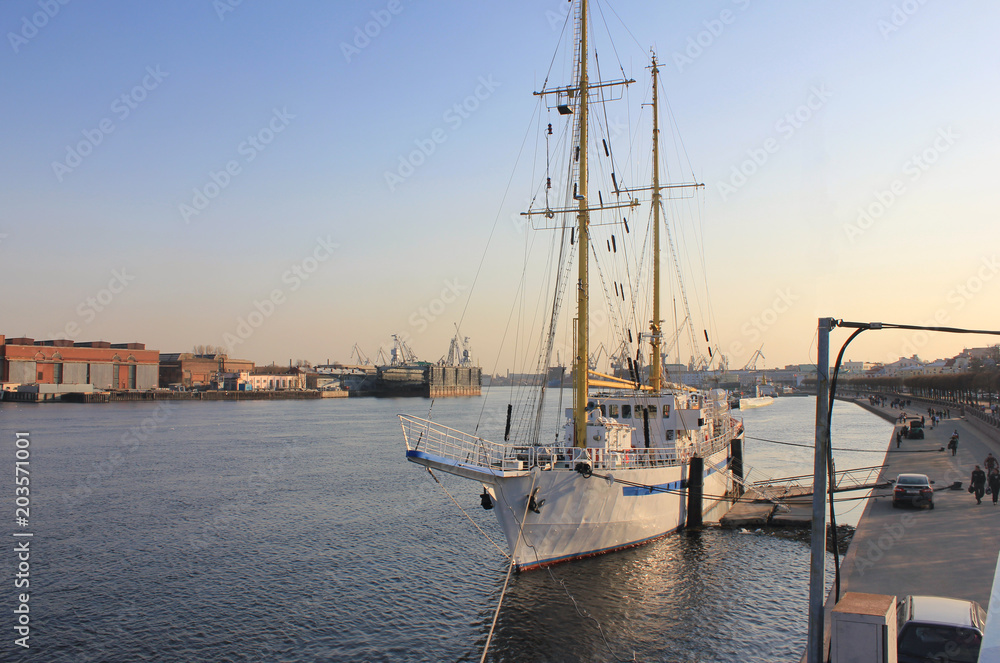 Sail Boat on Water at City Embankment. Luxury White Ship on Waterfront Embankment in Saint Petersburg, Russia. Vintage Tourist Yacht or Small Cruise Ship for Active Vacation or Tours before Sunset.