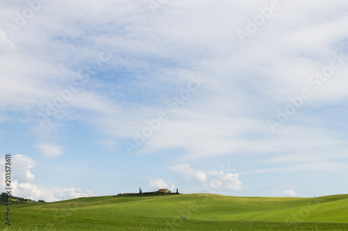 Italian landscape with green fields in spring  holidays in Italy in Umbria and Tuscany. Travel drive in the Tuscany countryside with soft green hills and blue skies. Calm and relax holidays in Italy