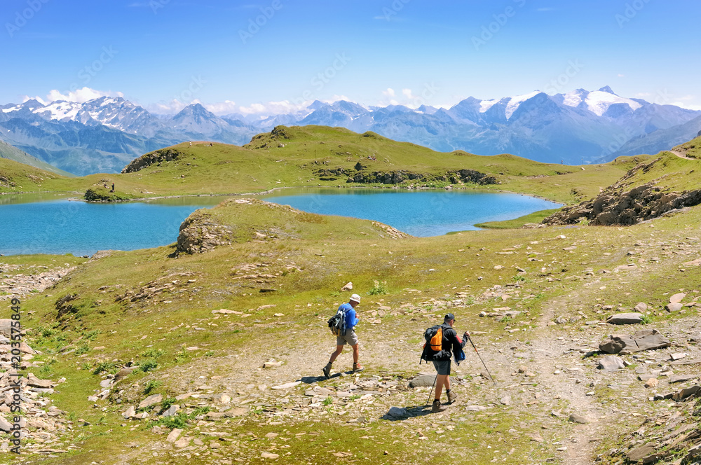 Fototapeta premium hikers walking next to lake in a beautiful view on peaks mountain
