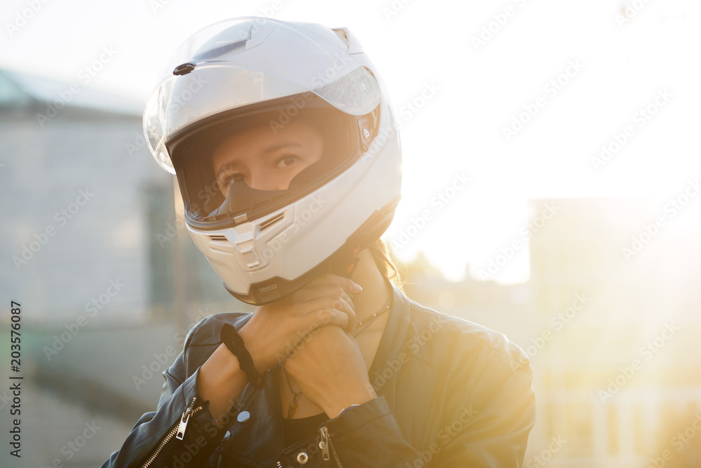 girl in black leather jacket puts on white helmet