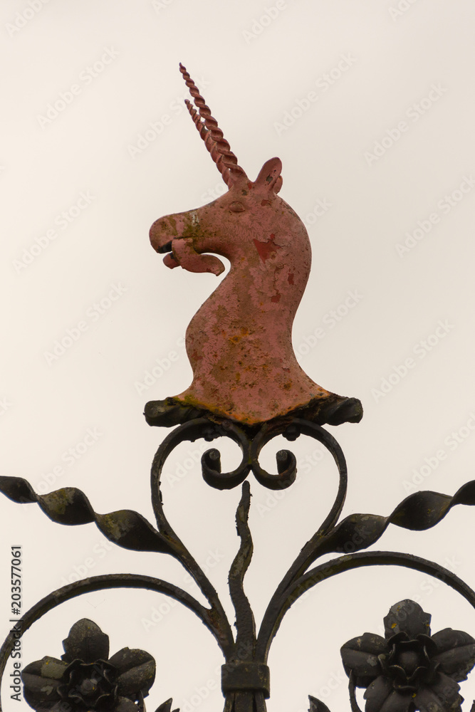 Fototapeta premium red metal unicorn crest with dual spiral horns on wrought iron decoration